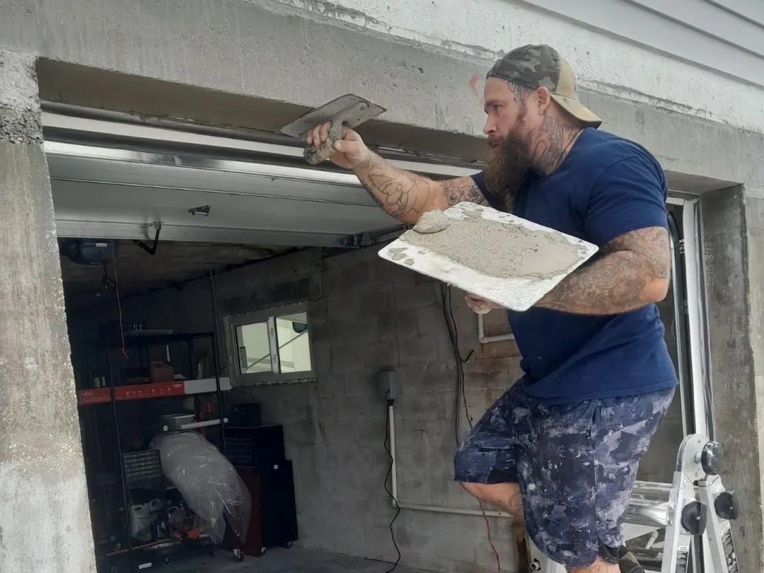 Daniel Vowell applying a stucco finish to a garage entranceway